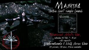 Mankind gig poster. Black and white photograph of gothic witch like woman with her arms outstretched and head looking up towards the sky with her eyes closed. Standing in a creek with a bank of slab rocks. White writing and a triangle and eye symbol in the left corner.