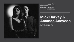 Mick Harvey poster. Grey background & white text. Black and white photo of Mick and Amanda Acevedo who are dressed in black and looking sternly at the camera.