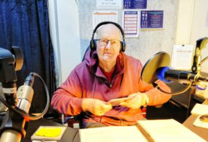 The Ghost Rider behind the mic in studio 2, wearing headphones and holding CDs