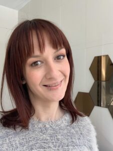 A white woman with red hair smiling at the camera
