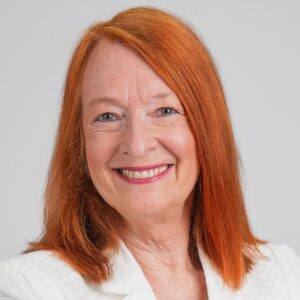 Kaye headshot, a white woman with orange shoulder length hair smiling at the camera