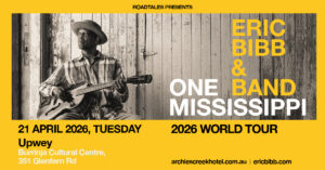 Eric Bibb Burring banner poster. Black and white phot of Eric sitting on a chair playing and acoustic guitar. Surrounded by a boarder of yellow with black, white and yellow text. 